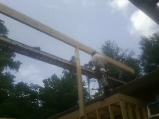 Carpenter setting a ridge beam over a new addition frame — Ice Dam Removal by Roofing Brothers in Monarch