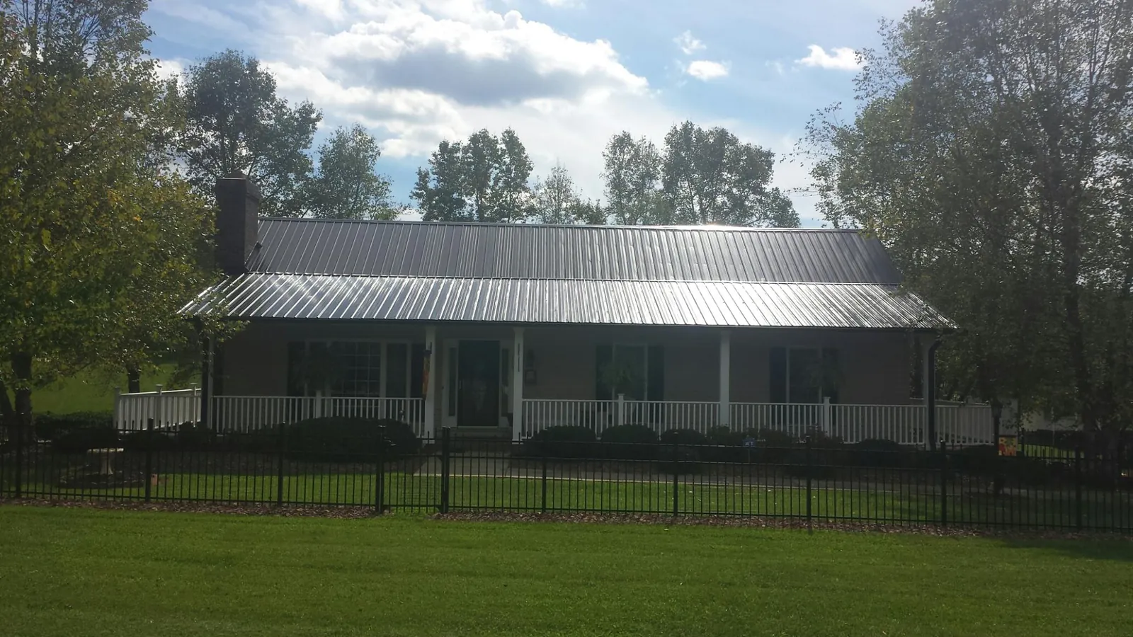 Gray metal roof on a brick ranch with a full width front porch — Gutter Guard Installation work by our crew in Monarch