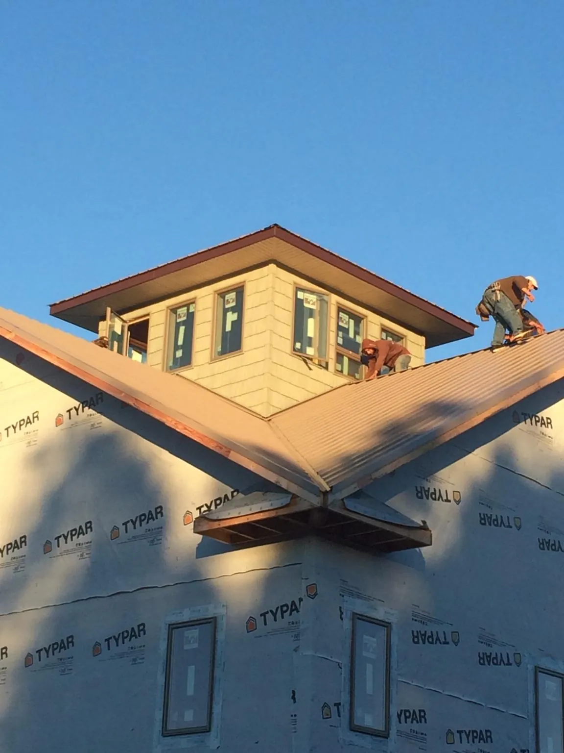 Roofers working around a rooftop cupola on a new metal roof at sunset — Roof Waterproofing in Monarch by Roofing Brothers